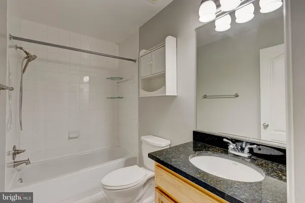 a bathroom with a granite countertop sink toilet a mirror and shower