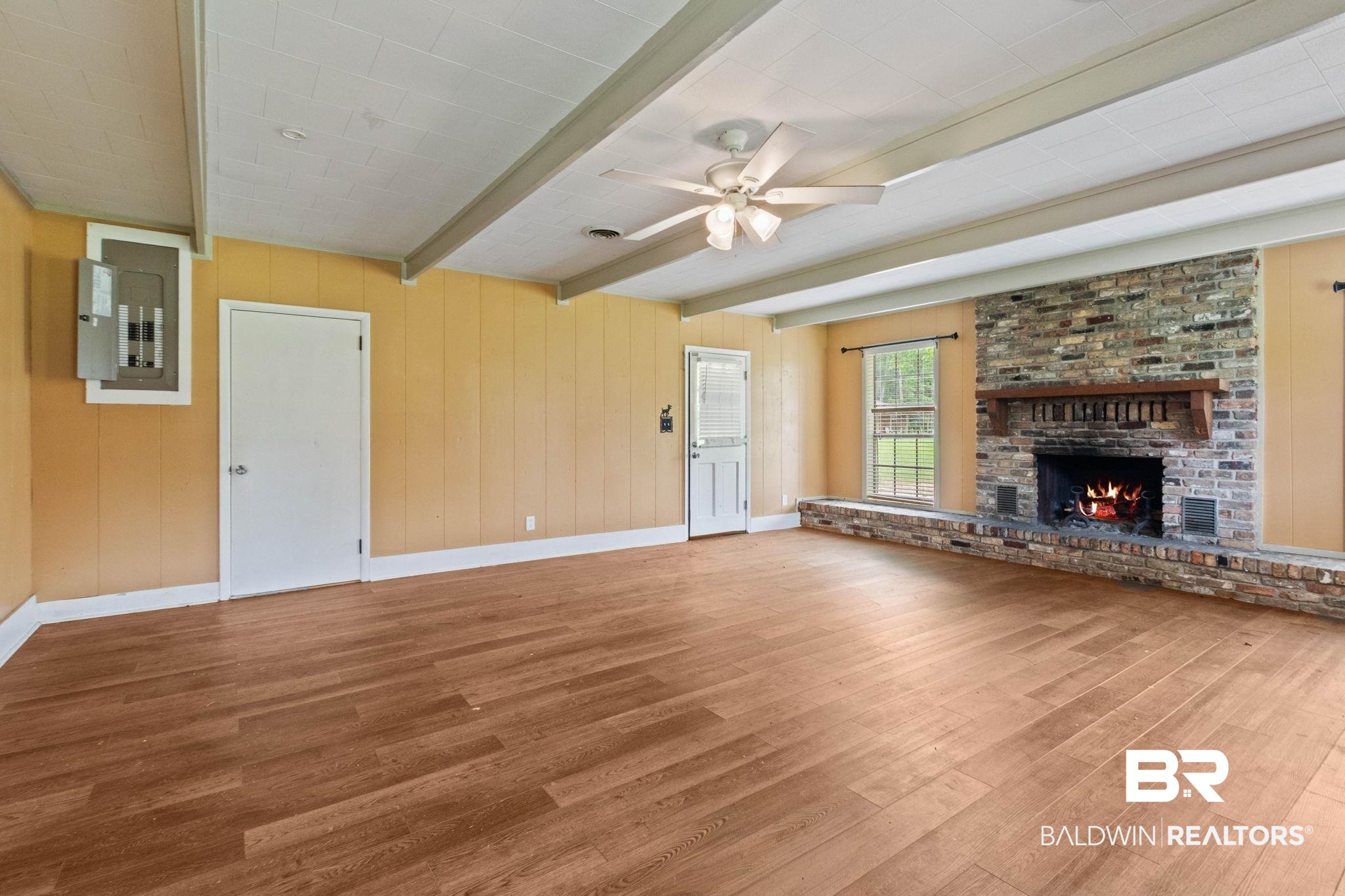 384 Old Bratt Road Atmore, AL 36502 - Photo 12 of 64 Spacious room featuring wood-finish flooring, a stone fireplace with a wood mantle, exposed ceiling beams, and a ceiling fan