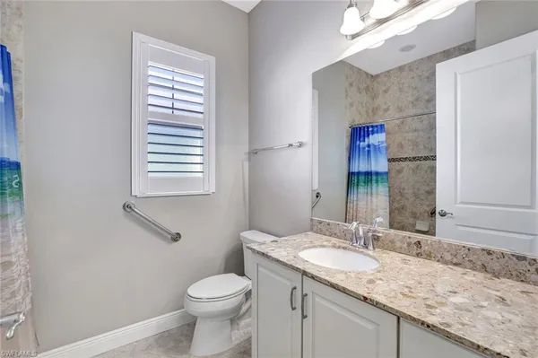 a bathroom with a granite countertop toilet sink and mirror