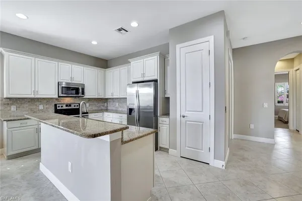 a kitchen with stainless steel appliances granite countertop a refrigerator oven a sink a granite counter tops and white cabinets