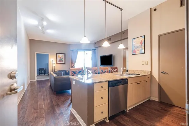 a view of living room with granite countertop stainless steel appliances lots of counter space and wooden floor