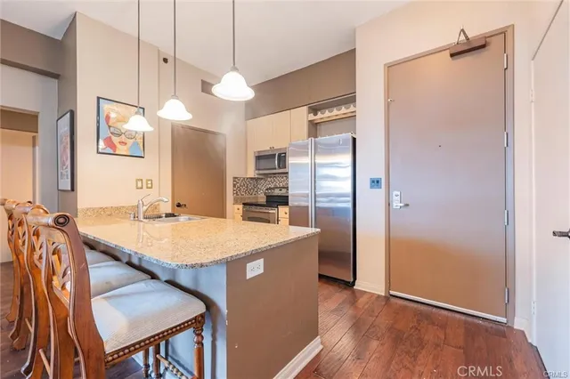 a kitchen with stainless steel appliances granite countertop a table chairs and a refrigerator