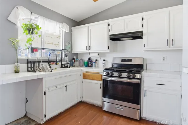 a kitchen with stainless steel appliances white cabinets a sink and a stove