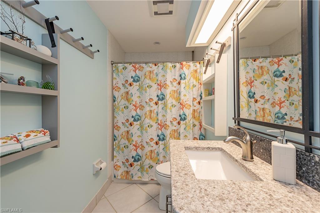 6624 Trident Way, Unit G5 Naples, FL 34108 - Photo 12 of 18 a bathroom with a granite countertop sink a toilet and shower curtain