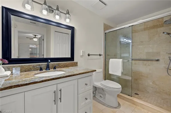 a bathroom with a granite countertop sink a toilet and a mirror