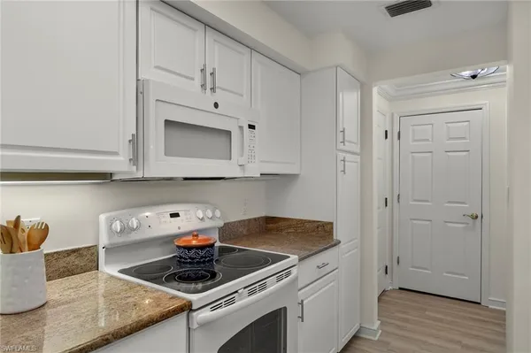 a kitchen with granite countertop white cabinets and white appliances