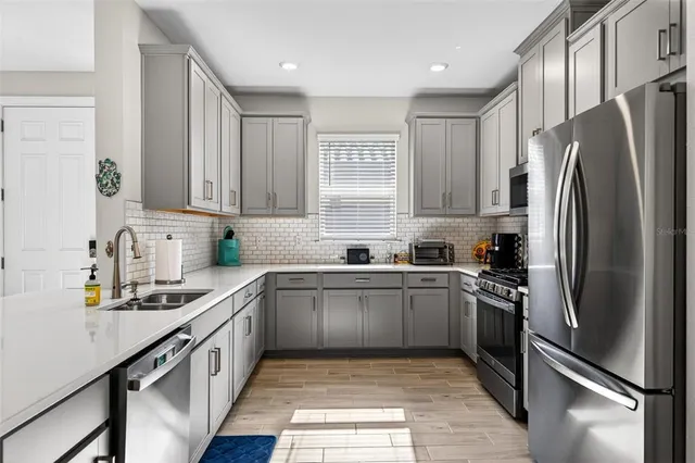 a kitchen with stainless steel appliances granite countertop a sink a stove and a refrigerator