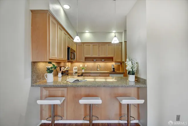 a bedroom with a bed a dresser and potted plants with the wooden floor
