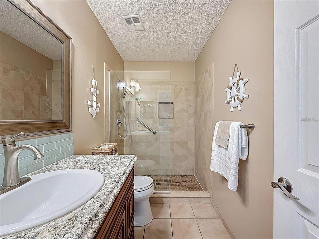 9981 Eagles Point Circle, Unit 4 Port Richey, FL 34668 - Photo 7 of 32 a bathroom with a granite countertop sink a mirror and shower