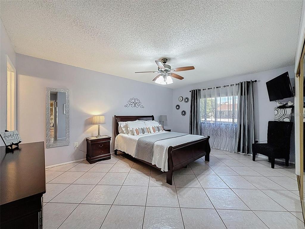 9981 Eagles Point Circle, Unit 4 Port Richey, FL 34668 - Photo 8 of 32 a spacious bedroom with a bed and a flat screen tv