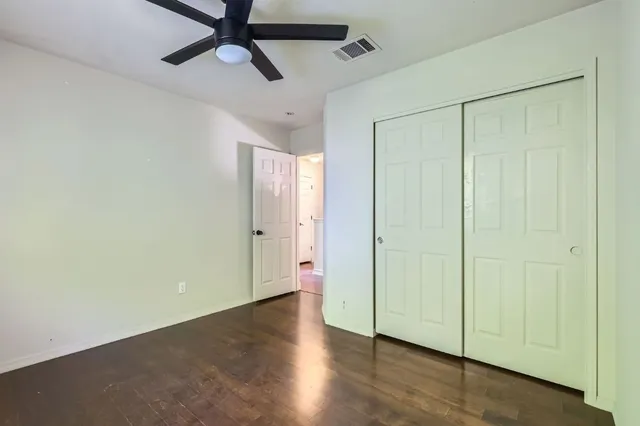 an empty room with wooden floor closet and windows