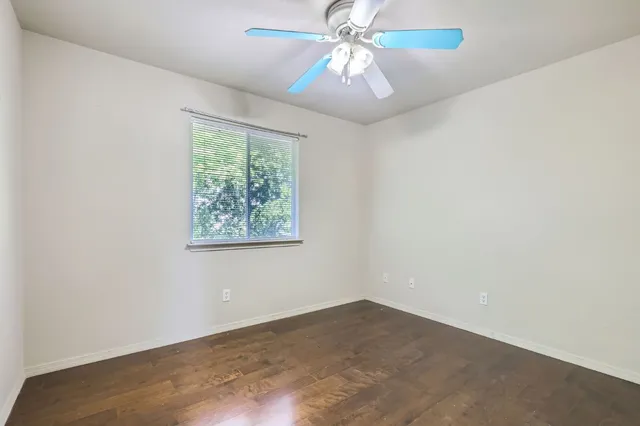 an empty room with a window and a fan
