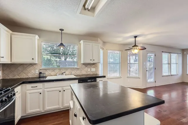 a kitchen with stainless steel appliances granite countertop a sink a stove and cabinets