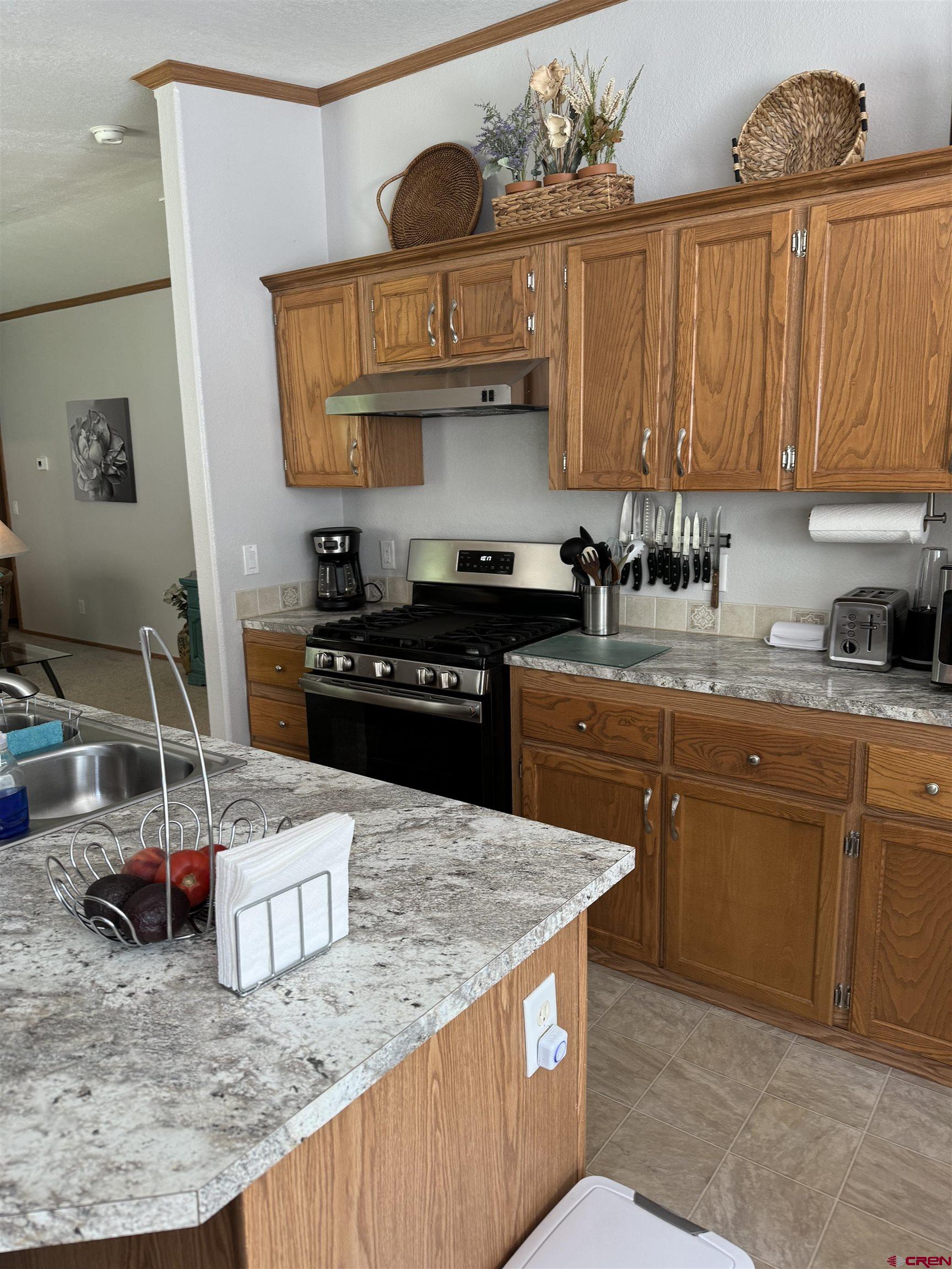 901 6530 Road, Unit 1307 Montrose, CO 81401 - Photo 2 of 14 a kitchen with granite countertop a sink a stove and wooden cabinets