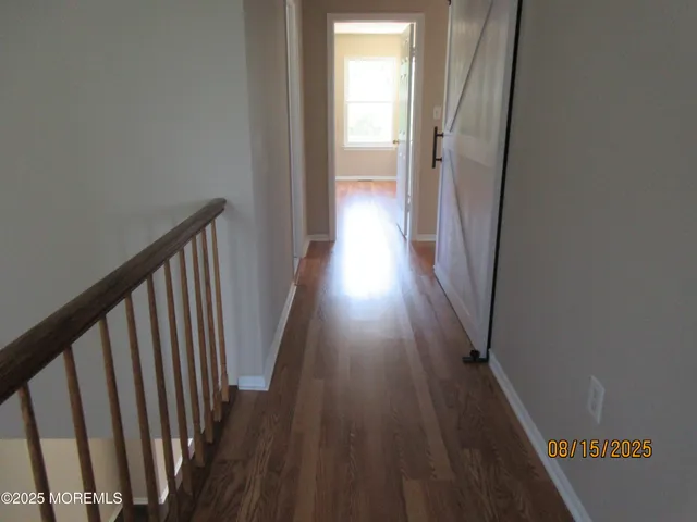 a view of a hallway with wooden floor and staircase