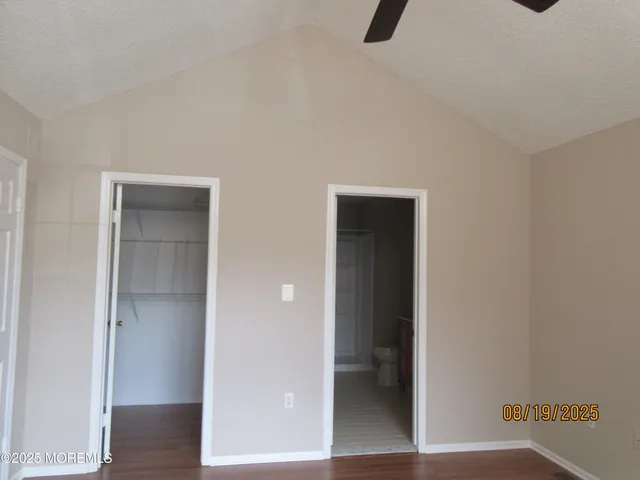 a view of an empty room with wooden floor and closet