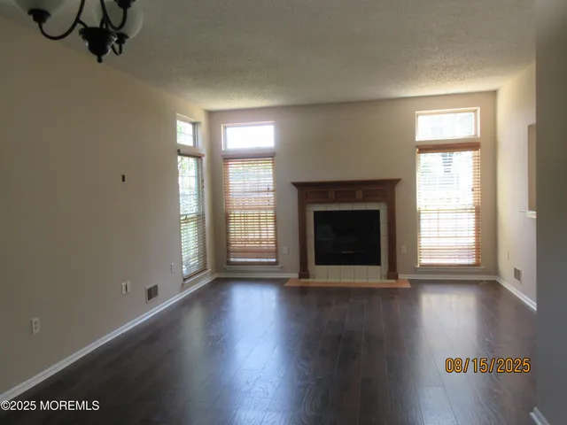 an empty room with wooden floor fireplace and windows