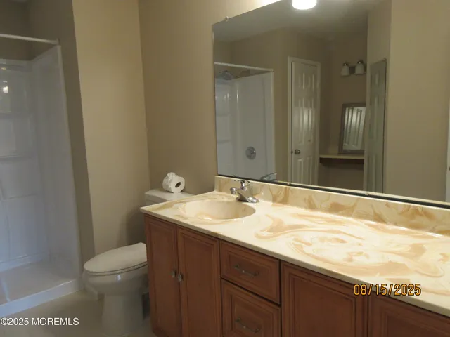 a bathroom with a granite countertop sink toilet and mirror
