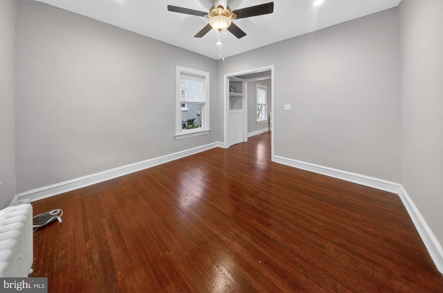1353 Kennedy Street Northwest Washington, DC 20011 - Photo 7 of 32 an empty room with wooden floor chandelier fan and windows