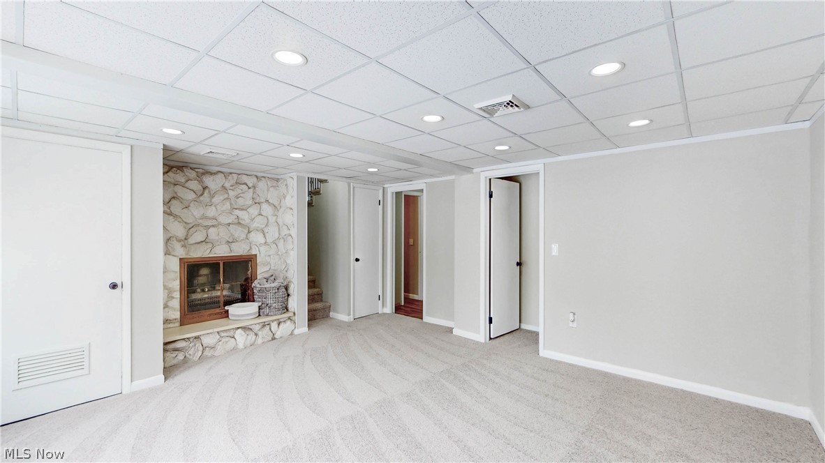 3312 Bancroft Road Akron, OH 44333 - Photo 38 of 50 Unfurnished living room with recessed lighting, light colored carpet, a stone fireplace, and a drop ceiling