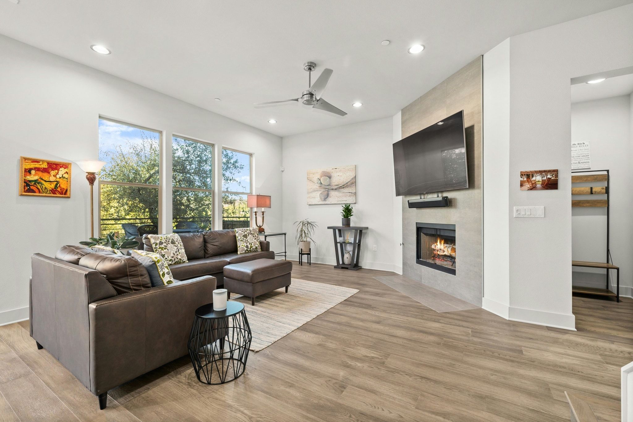 8110 Ranch Road 2222, Unit 92 Austin, TX 78730 - Photo 3 of 40 Bright living area featuring wood-finish flooring, a modern fireplace with a tiled surround, recessed lighting, a ceiling fan, and large windows