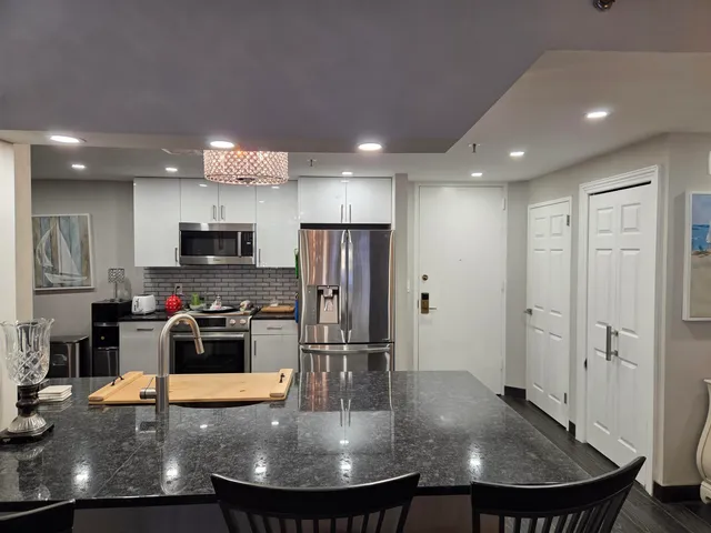 a view of a kitchen with kitchen island a sink stainless steel appliances and cabinets
