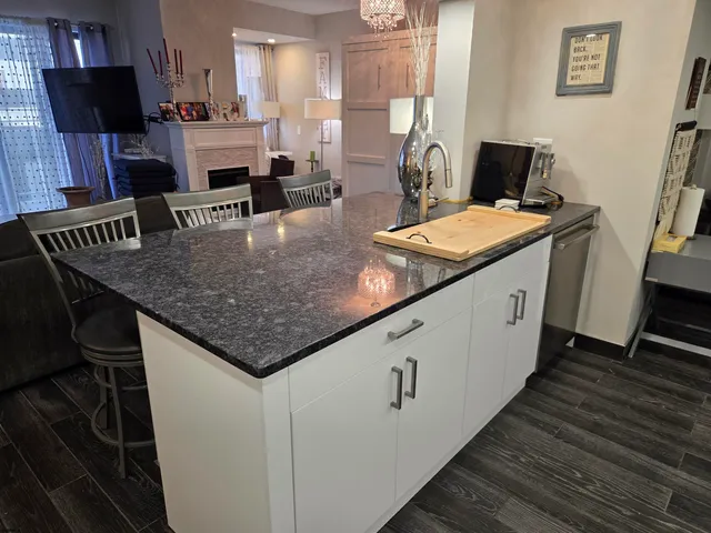 a kitchen with stainless steel appliances granite countertop a sink dishwasher stove a refrigerator and a dining table with wooden floor