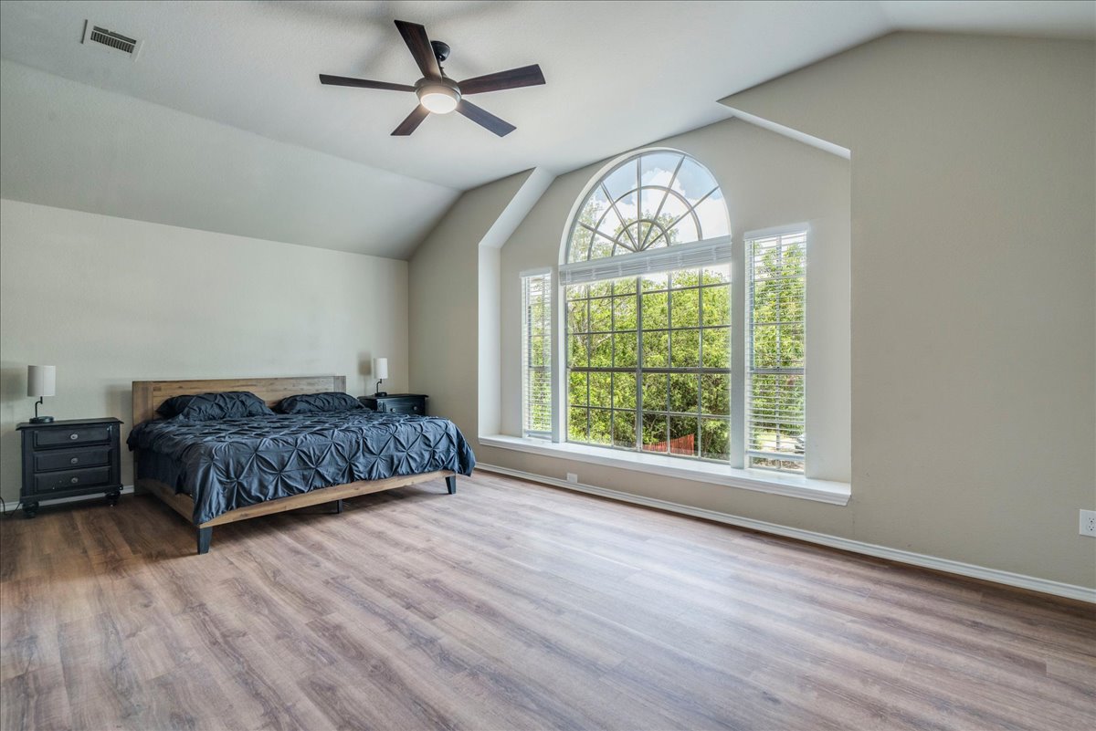 9300 Tea Rose Trail Austin, TX 78748 - Photo 19 of 33 A tranquil primary suite offers lofty ceilings and a grand arched window overlooking lush greenery.