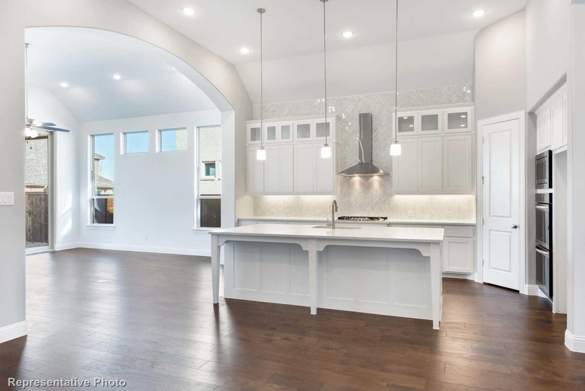 a large white kitchen with lots of counter space wooden floor and appliances