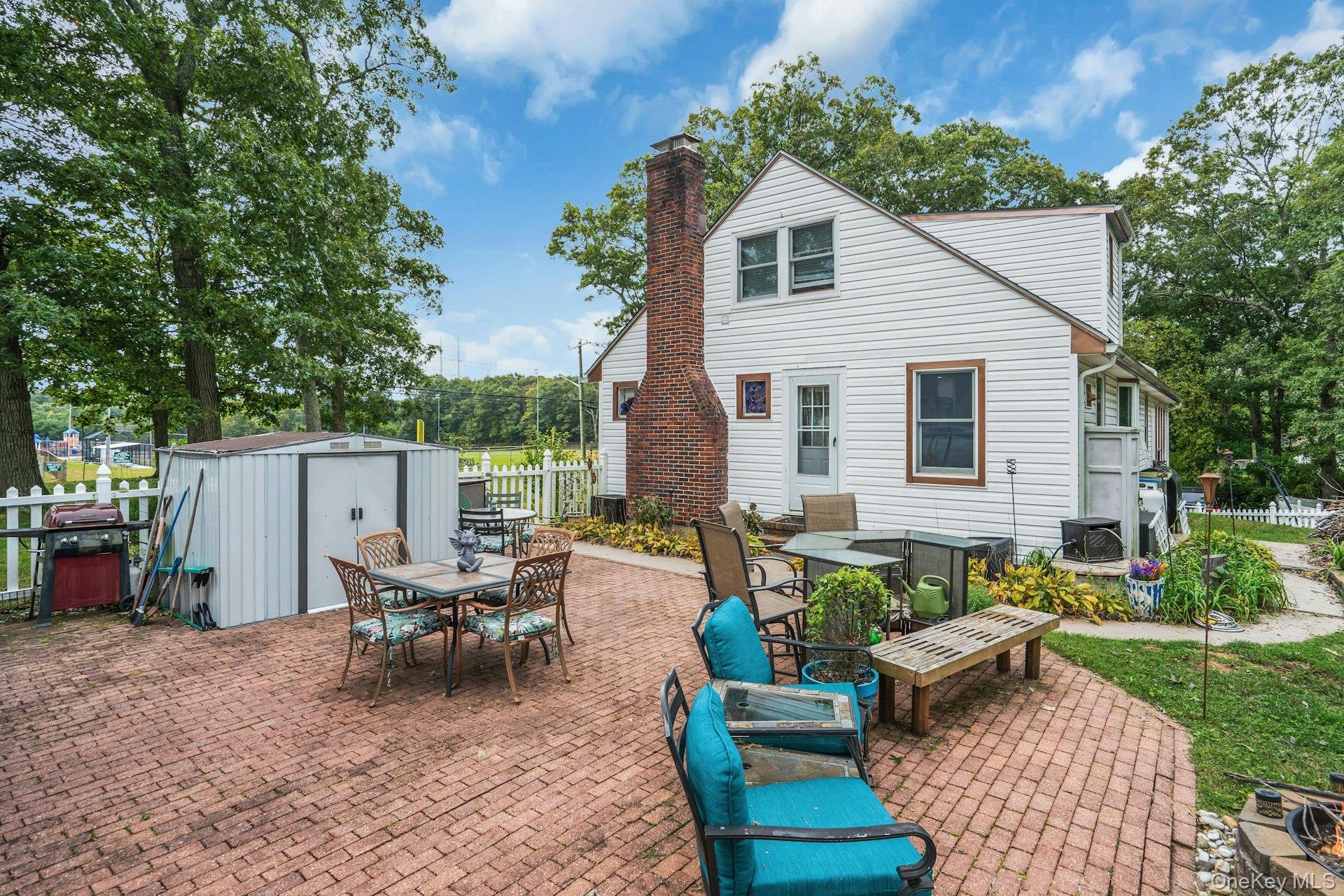 79 Wicks Road Commack, NY 11725 - Photo 29 of 34 Expansive brick paver patio featuring a white picket fence, and a storage shed