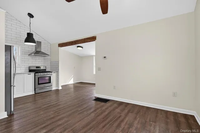 an empty room with wooden floor ceiling fan and window