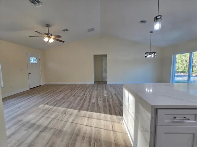an empty room with wooden floor fan and windows