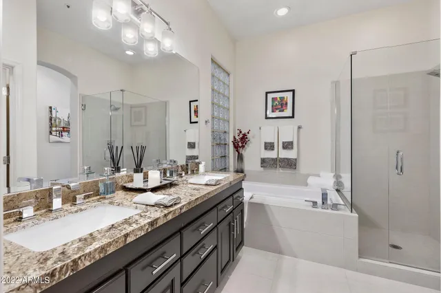 a bathroom with a granite countertop double vanity sink a mirror and a bathtub