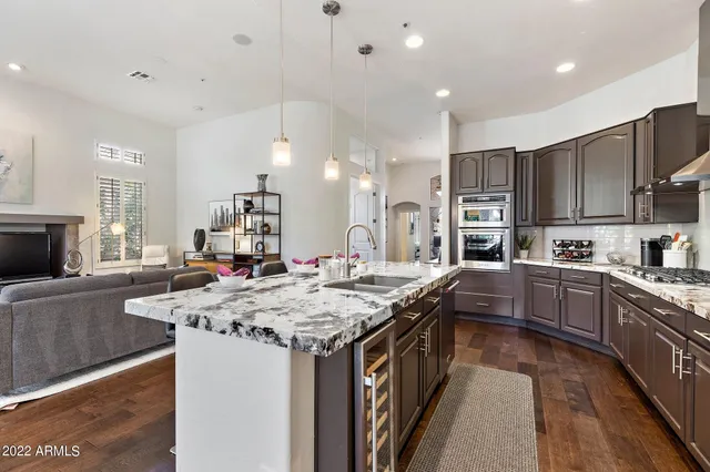a kitchen with stainless steel appliances granite countertop a kitchen island a stove a sink a oven and a refrigerator