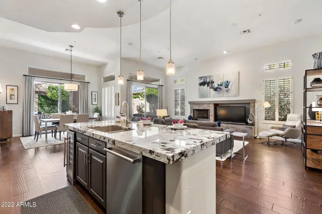 a open kitchen with a stove a sink a kitchen island with chairs and wooden floor