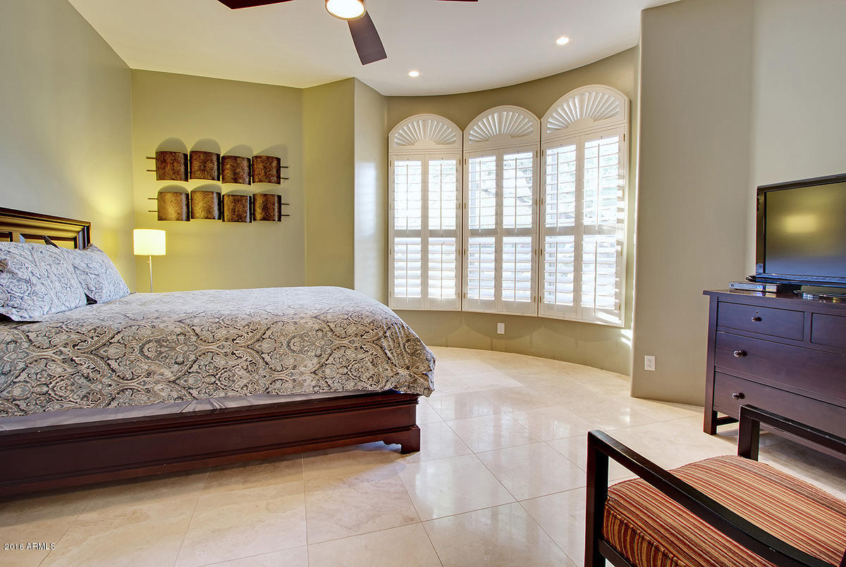 4805 East Pebble Ridge Road Paradise Valley, AZ 85253 - Photo 24 of 37 a spacious bedroom with a bed and a flat tv screen on dresser