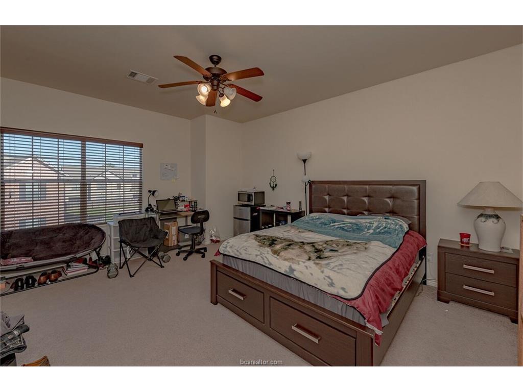 1425 West Villa Maria Road, Unit 602 Bryan, TX 77801 - Photo 7 of 12 a bedroom with a bed a couch and a chandelier