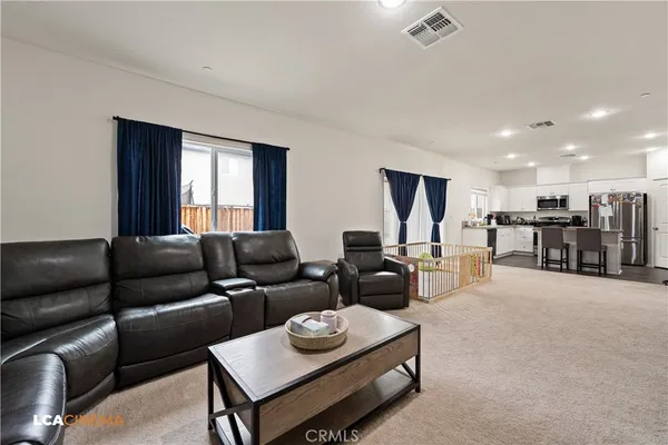 a living room with furniture kitchen view and a window
