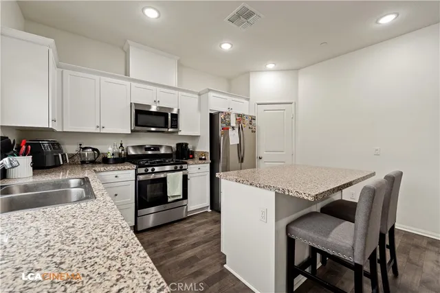 a kitchen with granite countertop a stove top oven a sink a dining table and chairs