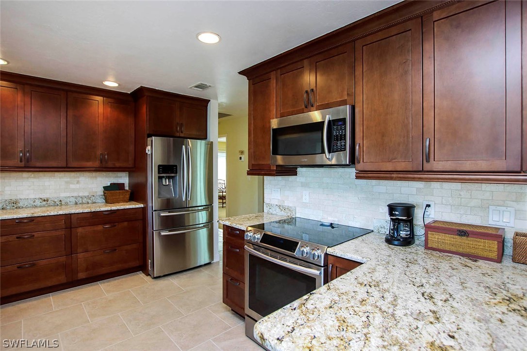 1133 Sand Castle Road Sanibel, FL 33957 - Photo 3 of 28 a kitchen with stainless steel appliances granite countertop a refrigerator stove and microwave