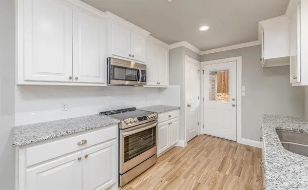 a kitchen with granite countertop a stove top oven microwave and cabinets