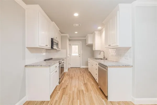 a kitchen with granite countertop a sink a stove top oven a counter space and cabinets