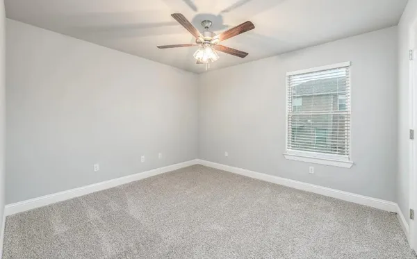 an empty room with a chandelier fan and windows