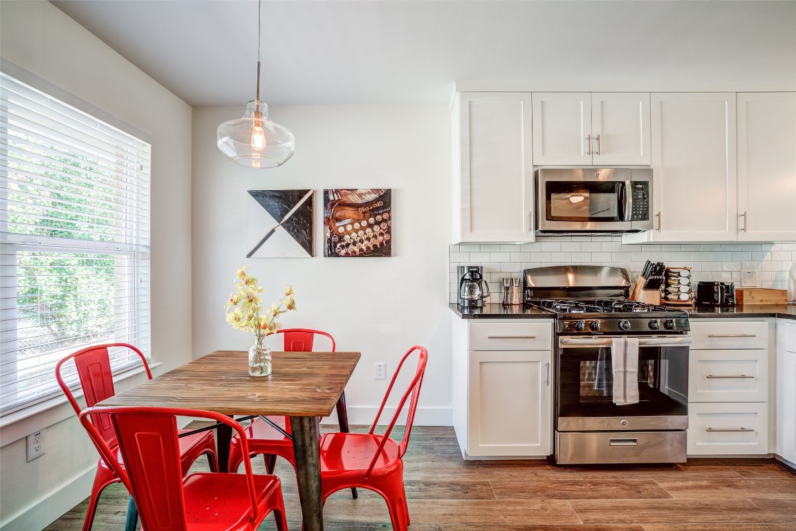 a kitchen with stainless steel appliances granite countertop a stove a microwave a dining table and chairs