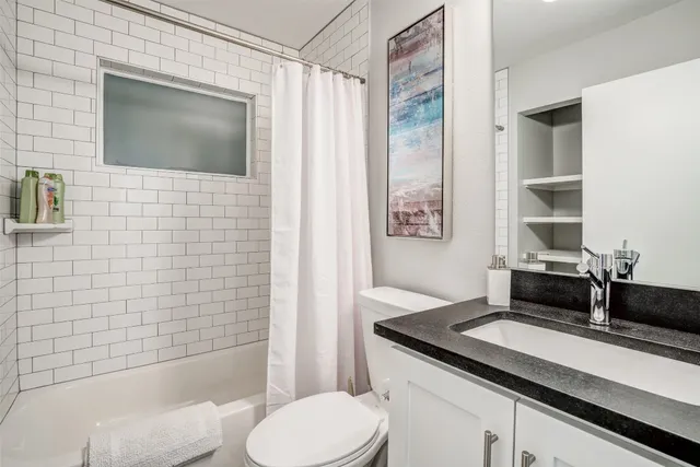 a bathroom with a granite countertop sink toilet and shower