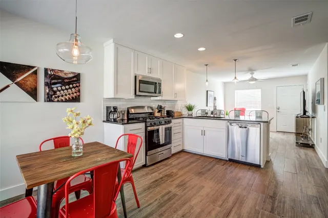 a kitchen with stainless steel appliances granite countertop a kitchen island hardwood floor sink stove dining table and chairs