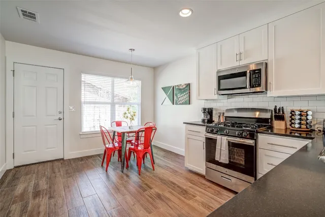 a kitchen with stainless steel appliances a stove a sink dishwasher a microwave oven with a dining table and chairs