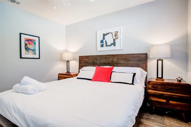 a bedroom with a bed and a lamp on dresser