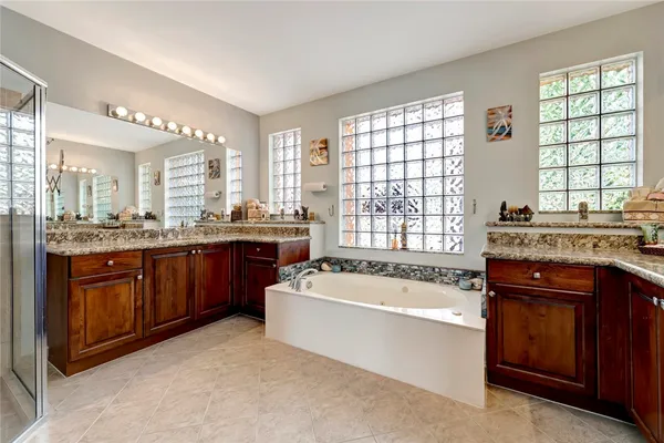 a bathroom with a granite countertop bathtub sink double vanity and window