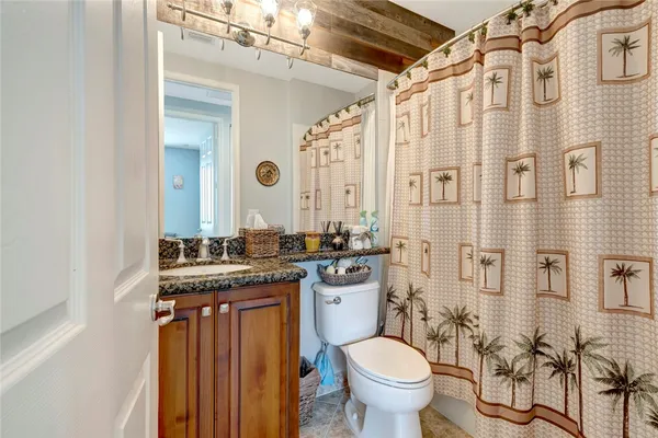 a bathroom with a granite countertop toilet sink and mirror